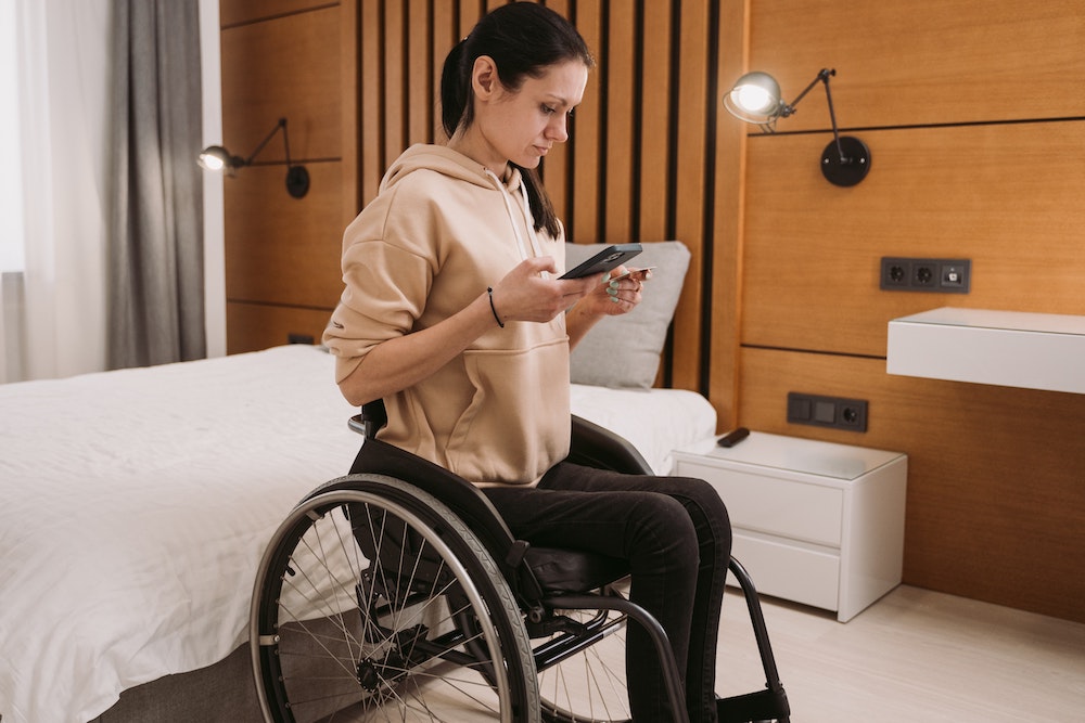 acessibilidade em hospedagem - mulher cadeirante em quarto de hotel acessível